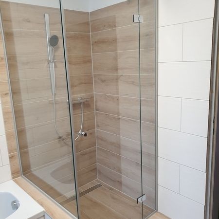 Glasdusche auf hellbraunen Fliesen