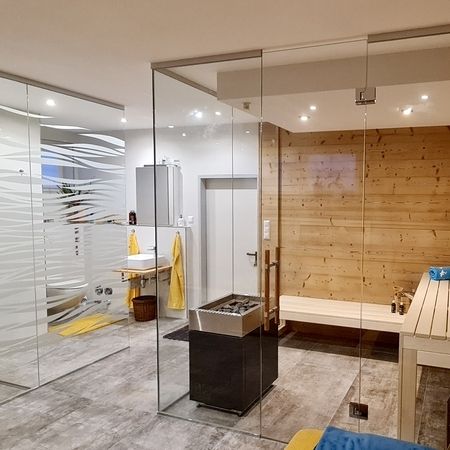 Raumansicht einer mit Glas getrennten Sauna, Glaswand mit Wellenmuster im Hintergrund