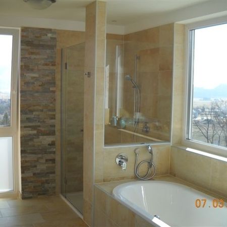 Bad mit terracottafarbenen Fliesen, Badewanne und Raumtrennung mit Glastür-Dusche