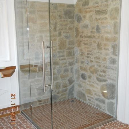 Glasdusche an Steinwand und Backsteinboden