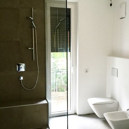 Dusche links mit mittiger Glastür, rechts Toilette