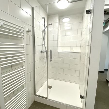 Heizung und Glasdusche in hellem Badezimmer