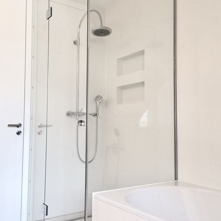 Minimalistische Glasdusche mit weißen Fliesen