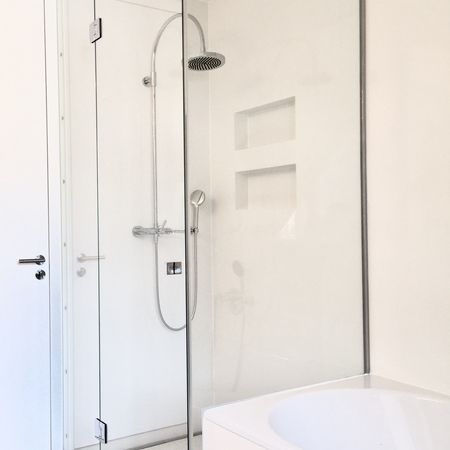 Minimalistische Glasdusche mit weißen Fliesen