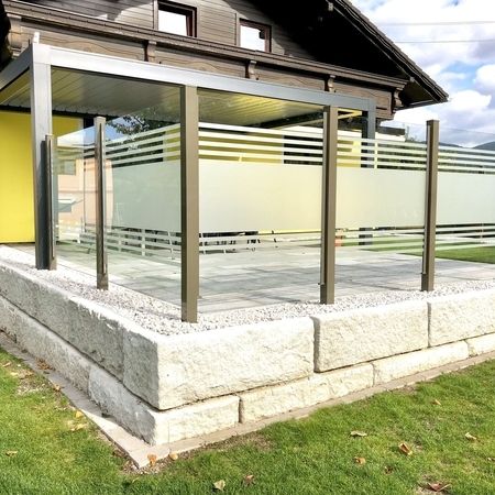 Gestreiftes Glasgeländer einer Steinterrasse, Ansicht von außen links