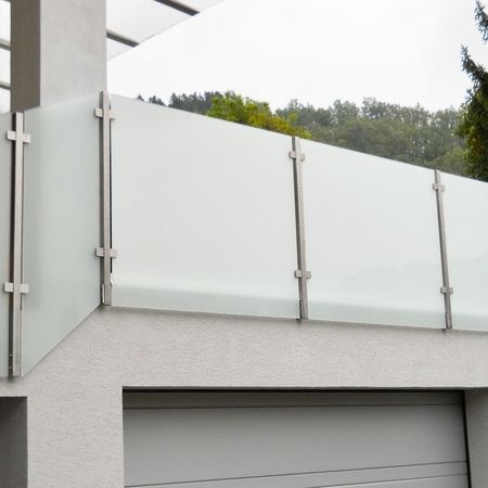 Helles Balkon-Glasgeländer an weißer Hausfassade