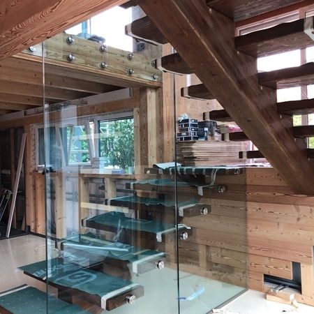 Glastrennwand mit Treppe auf hölzernen Balken und Böden