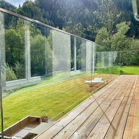 Linke Innenansicht eines Holzterassen-Geländers mit Blick auf eine grüne, sonnige Landschaft