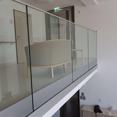 Glasgeländer vor einem Obergeschoss mit Sessel