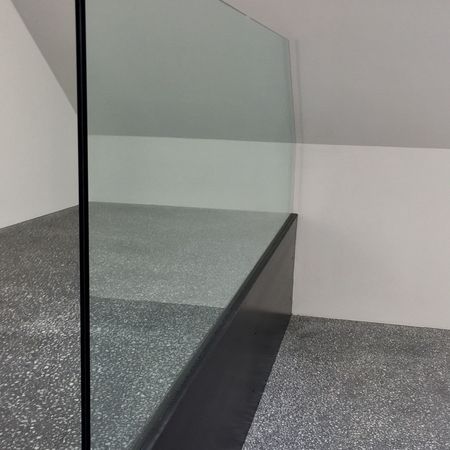 Glas-Raumtrenner in leerem Raum mit Dachschräge