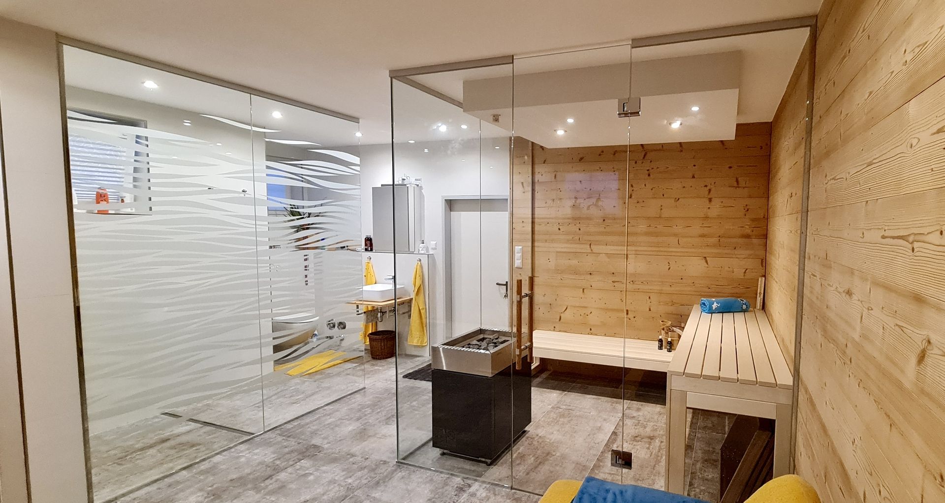 Raumansicht einer mit Glas getrennten Sauna, Glaswand mit Wellenmuster im Hintergrund