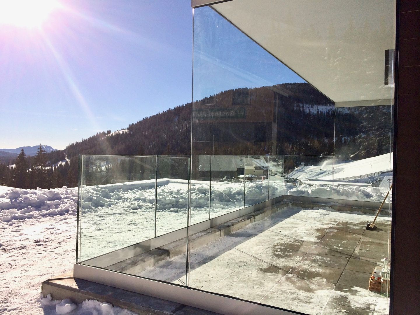 Glasgeländer vor beschneiter Landschaft